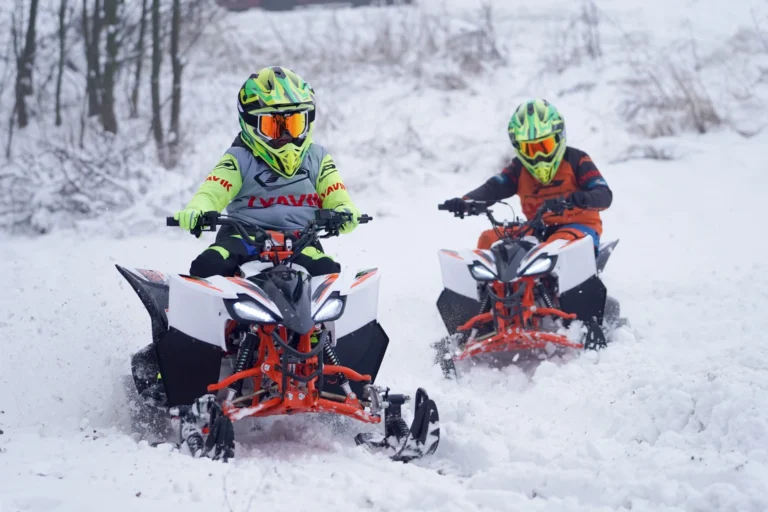 Dwa quady KAYO AT125 z pakietami snow kit podczas wyścigu na śniegu